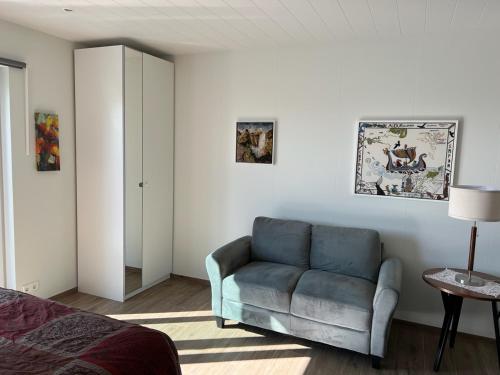 a bedroom with a blue chair and a bed at Lækjarkot Rooms and Cottages with Kitchen in Borgarnes