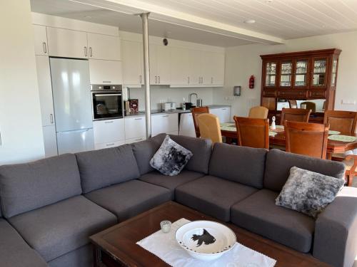 a living room with a gray couch and a kitchen at Lækjarkot Rooms and Cottages with Kitchen in Borgarnes