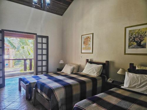 Cette chambre comprend 2 lits et une fenêtre. dans l'établissement Pousada Muriqui, à São Francisco Xavier