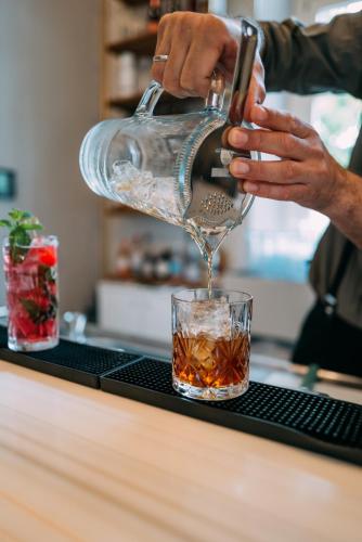 a person pouring a drink into a glass at Hotel Amalia - Boutique Hotel in Landshut