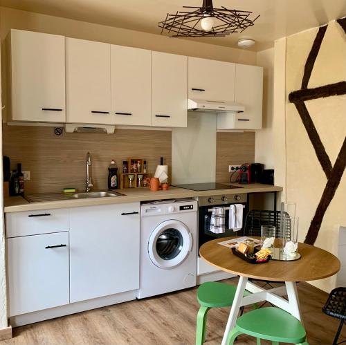 a kitchen with a washing machine and a table at La Bohè’m night in Villeneuve-la-Guyard