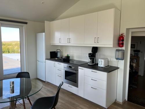 a kitchen with white cabinets and a table with chairs at Lækjarkot Rooms and Cottages with Kitchen in Borgarnes