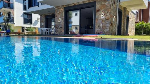 a swimming pool with blue water in front of a house at Villa Begonvil in Kusadası