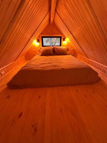 ein Schlafzimmer mit einem Bett in einem Holzzimmer in der Unterkunft Tiny house - Playa in Arauco
