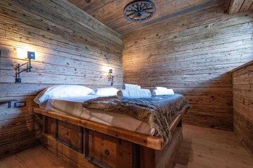1 dormitorio con 1 cama en una pared de madera en Casa Aquila, en Cortina dʼAmpezzo
