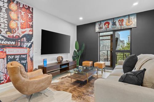 a living room with a couch and a tv at Skyline View, Pool, Gym, Balcony's, Walk to BWay! in Nashville