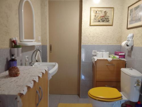 a bathroom with a yellow toilet and a sink at Eloise in Agriovótanon