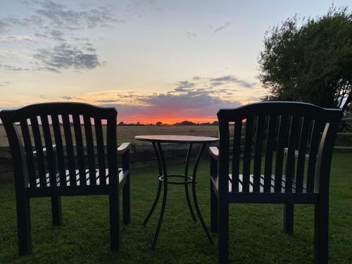 two chairs and a table in the grass with a sunset at Old Chapel Forge in Chichester