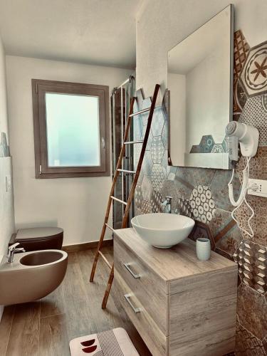 a bathroom with a sink and a toilet and a mirror at B&B Luchia in Orosei