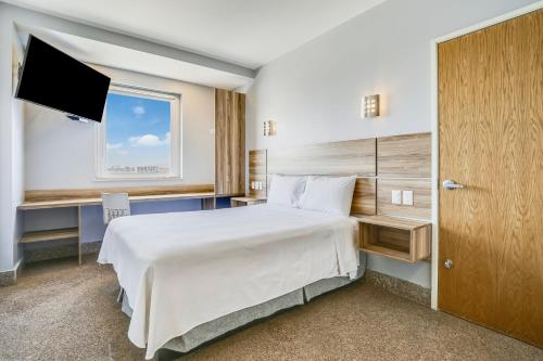 um quarto de hotel com uma cama e uma televisão em One Guadalajara Periferico Norte em Guadalajara