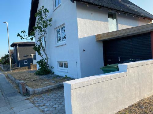 una casa blanca con una valla delante en 200 m til havet - fri adgang til svømmehal, en Thyborøn