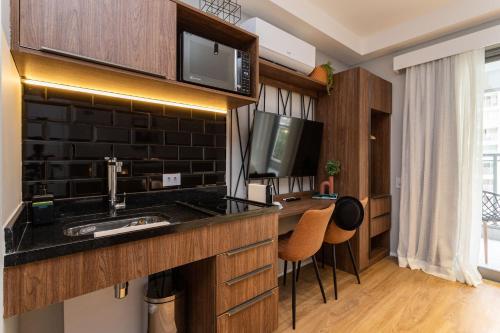 a kitchen with a sink and a counter with two chairs at Charlie Hotel Atmosfera Paulista in Sao Paulo
