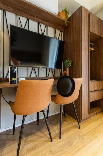 a room with a desk with two chairs and a television at Charlie Hotel Atmosfera Paulista in Sao Paulo