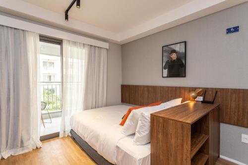 a bedroom with a bed with a desk and a window at Charlie Hotel Atmosfera Paulista in Sao Paulo