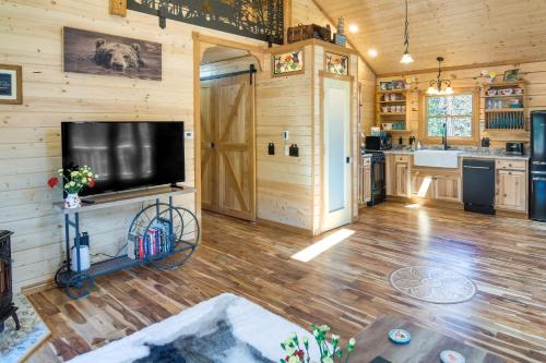 a living room with a flat screen tv on a wooden wall at Private Hot Tub and Pond Conifer Log Cabin in Conifer