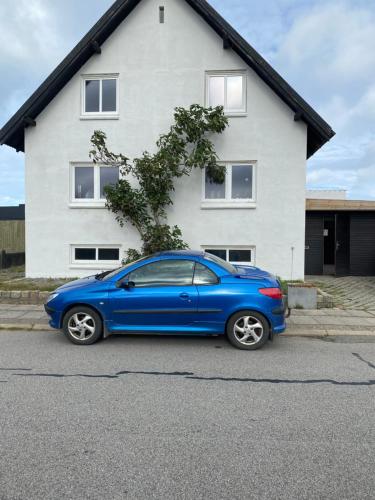 un coche azul estacionado frente a una casa en 200 m til havet - fri adgang til svømmehal, en Thyborøn