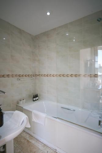 a white bath tub in a bathroom with a sink at The Sheldon B&B - FREE private parking in Eastbourne