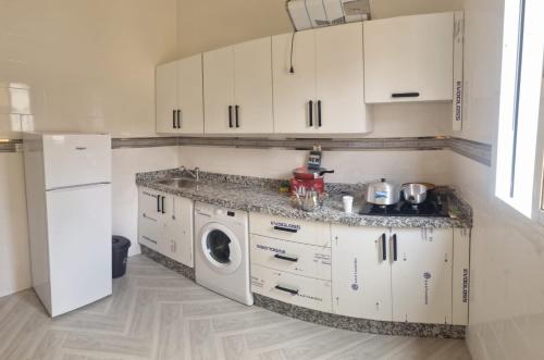 cocina con armarios blancos y lavadora en AL HOCEIMA appartement, en Alhucemas