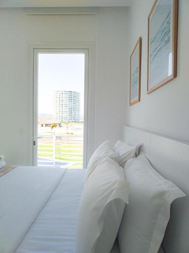 a white bedroom with a bed with white pillows at Karibao Resort Town in Playas