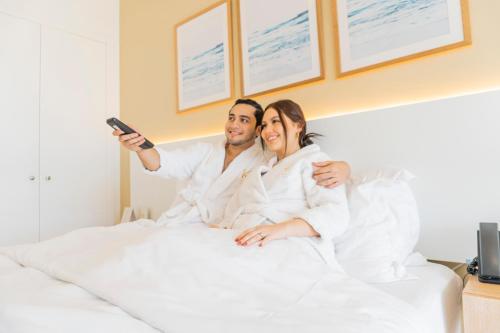 a man and woman sitting on a bed taking a picture at Karibao Resort Town in Playas