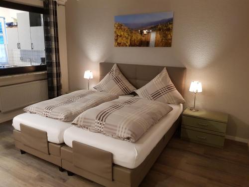 a bedroom with a bed with two lamps and a window at Gästehaus Vinum in Leiwen