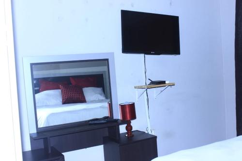 una camera da letto con un letto e una televisione a parete di Sun & Night a Empangeni