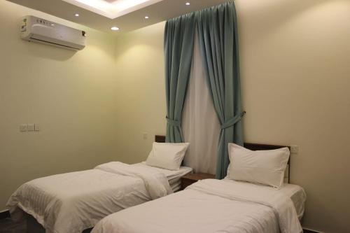 2 camas en una habitación con cortinas azules en شاليهات التميز الراقي en Al Hada