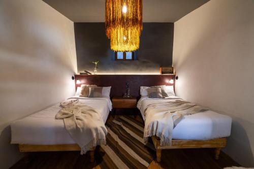two beds in a room with a chandelier at Casa Tunki in Cusco
