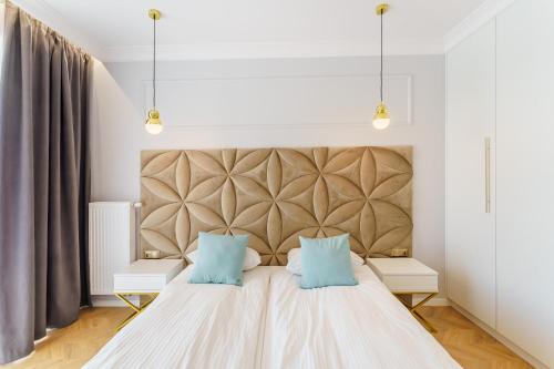 a bedroom with a large bed with two blue pillows at Apartament Westin House 303 in Kołobrzeg