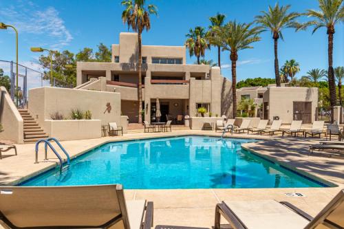 鳳凰城的住宿－Resort Style Living In Phoenix's Most Exclusive Gated Community!，棕榈树建筑前的游泳池