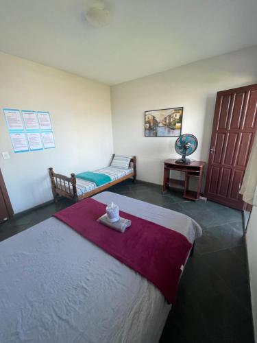 ガラパリにあるHope Hostel Guarapariのベッド1台、テーブル、ベッド1台、ベッド1台が備わる客室です。