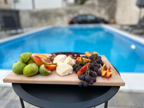 a plate of fruit and vegetables on a table next to a pool at Vila Hana in Stolac