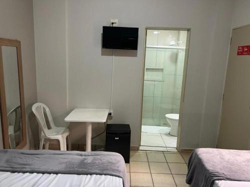 a room with two beds and a bathroom with a shower at Hotel Apiacas in Ribeirão Preto