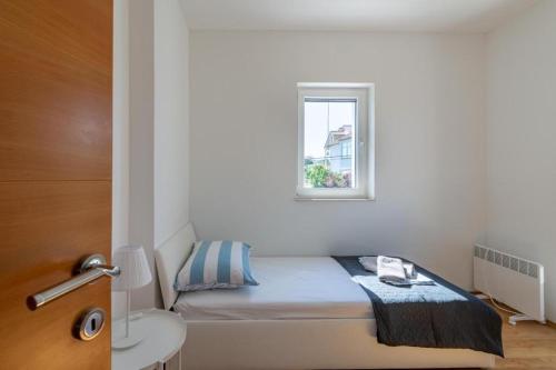 um pequeno quarto com uma cama e uma janela em Kuća Sanja em Murter