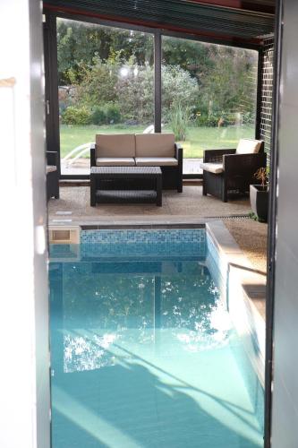 a swimming pool in front of a house with a couch at Gîte Lorengrain in Bruyères-et-Montbérault