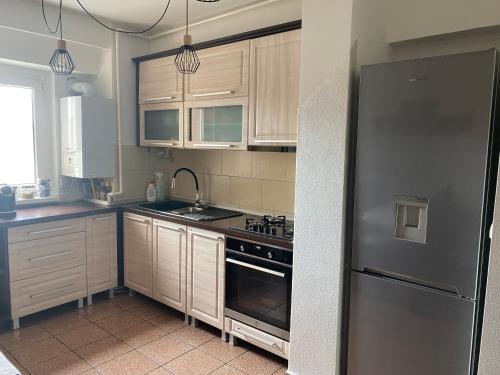 een keuken met houten kasten en een roestvrijstalen koelkast bij Apartament Cozma in Baia Mare