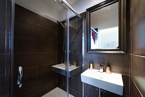 a bathroom with a shower and two sinks and a mirror at Central 5 Guest House in Budapest