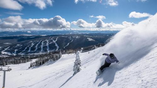 a man riding a snowboard down a snow covered slope at Fireside Lodge #215 by Bear Country in Sun Peaks