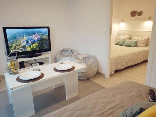 een woonkamer met een witte tafel en een televisie bij Small house with private park and yard in Terrugem