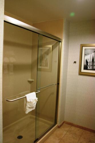 a glass shower in a hotel room with a towel at Hampton Inn & Suites West Point in West Point
