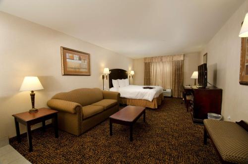 Hampton Inn & Suites Gallup في غالوب: غرفه فندقيه بسرير واريكه