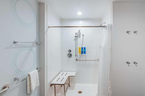 baño blanco con ducha y banco en TRU By Hilton Clarksville, en Clarksville
