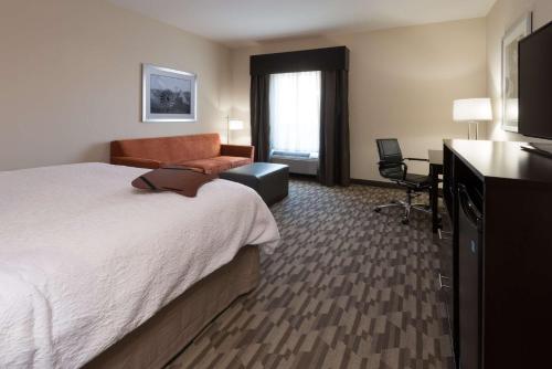 a hotel room with a bed and a chair and a television at Hampton Inn & Suites Albuquerque North/I-25 in Albuquerque