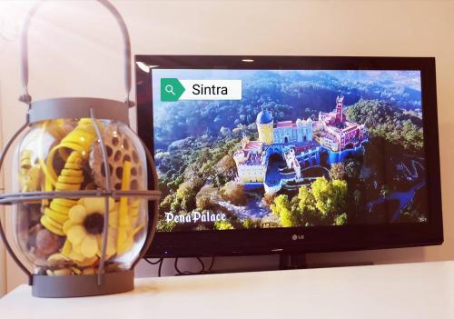 a television sitting on a table next to a bowl of food at Small house with private park and yard in Terrugem