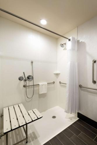 a white bathroom with a shower and a bench at Hampton Inn Morristown, I-81, TN in Morristown