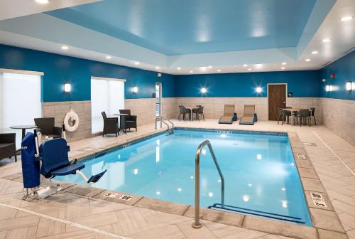 - une piscine dans le hall de l'hôtel avec des chaises et des tables dans l'établissement Hampton Inn Hastings, à Hastings