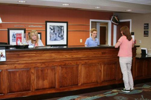 a woman standing at a cash counter in a waiting room at Hampton Inn Williamston in Williamston