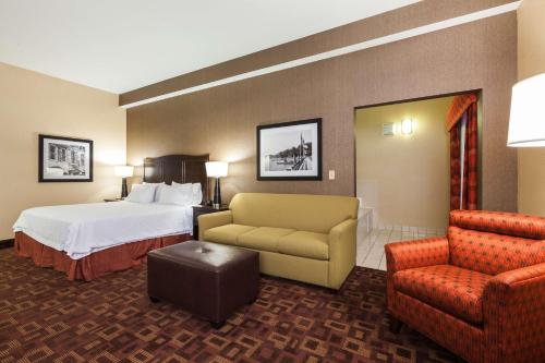 a hotel room with a bed and a couch and a chair at Hampton Inn Elkton in Elkton
