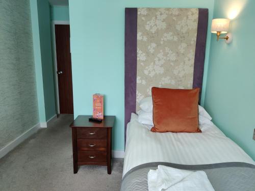a bed with an orange pillow and a night stand at Bingham Townhouse Hotel in Bingham
