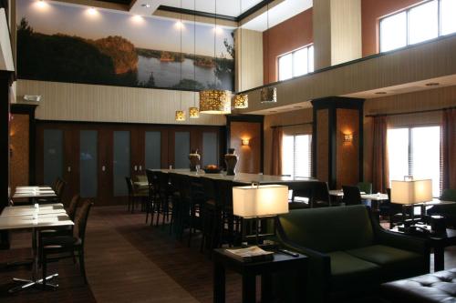 a restaurant with a bar and tables and chairs at Hampton Inn and Suites Peru in Peru